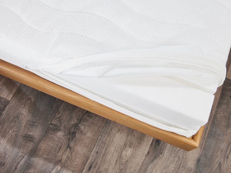Een witte matras met een houten frame.