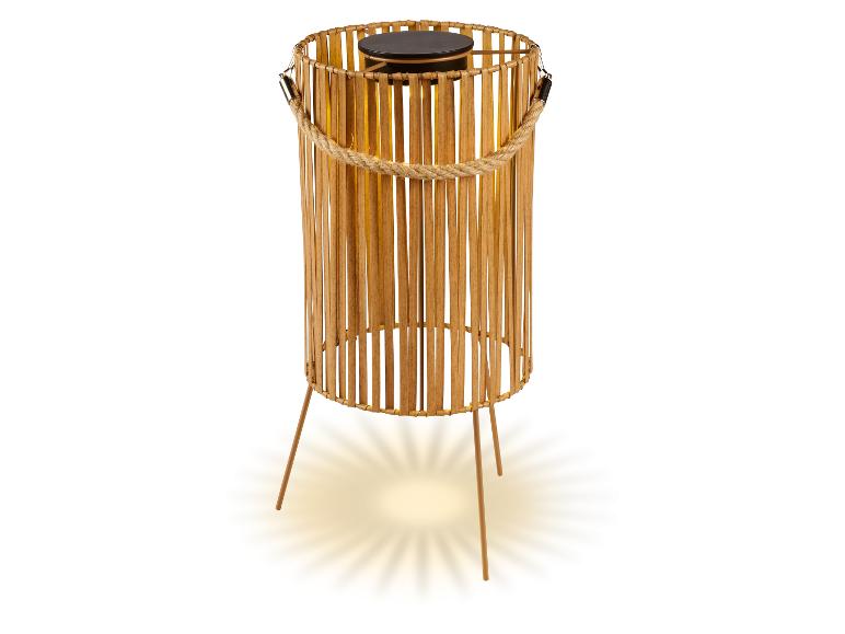 Bamboe solarlamp met touwgreep en drie poten, die warm licht uitstraalt.