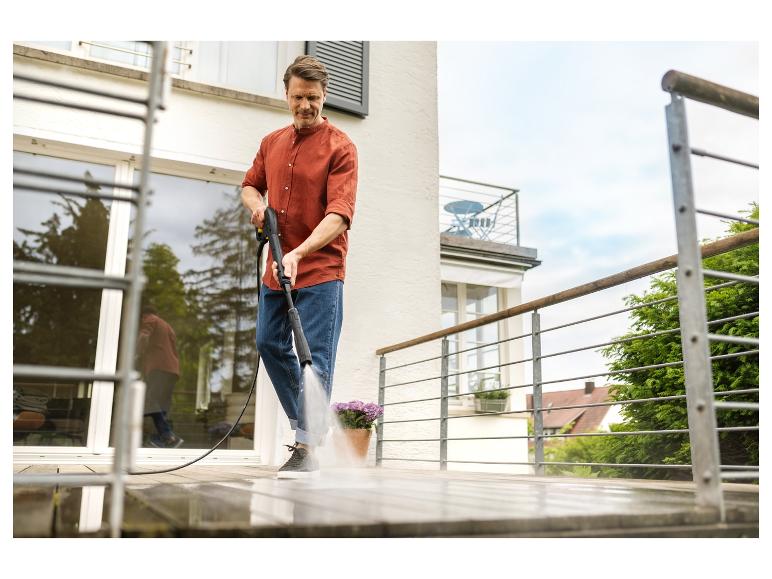 Man reinigt houten terras met hogedrukreiniger.