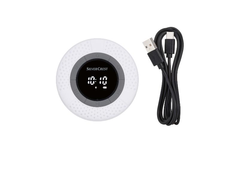Een ronde, witte Bluetooth-luidspreker van Silvercrest met een USB-oplaadkabel.
