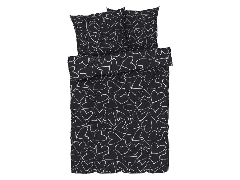 Zwarte dekbedovertrek met kussenslopen, bedrukt met witte hartjes.