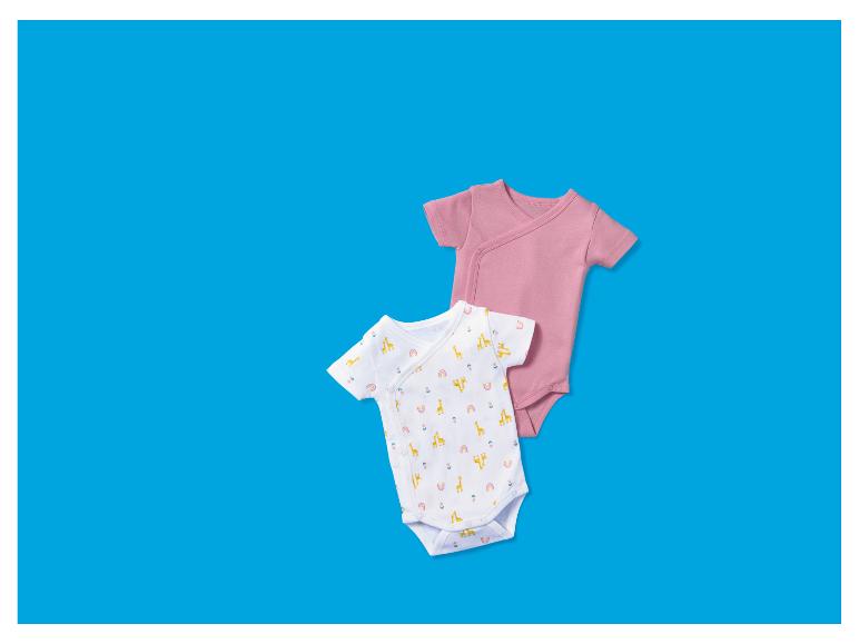 Twee babyrompertjes, één effen roze en één wit met giraffenpatroon.