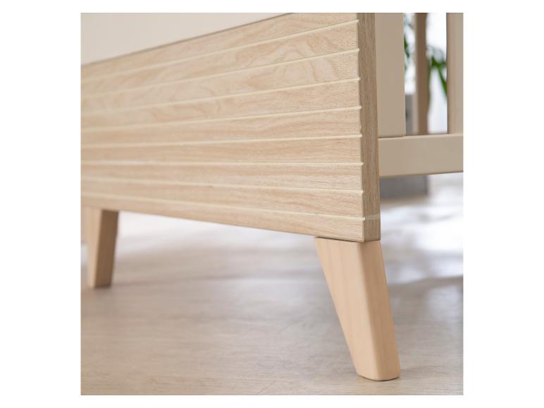 Lichte houten poten en zijpaneel van een babybedje.