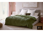 Slaapkamer met een groene gewatteerde sprei, witte kussens en een lichtroze muur.