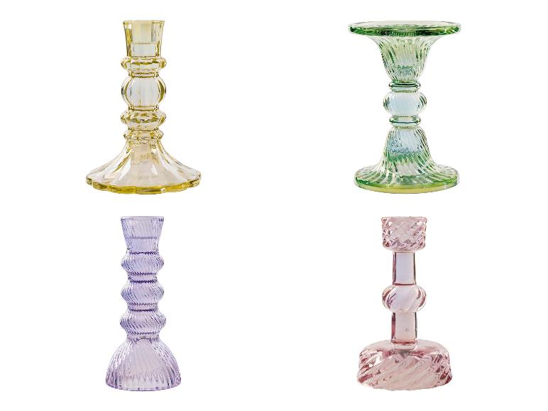 Vier glazen kandelaars in verschillende kleuren.