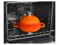 Oranje kookpot met deksel in een oven.