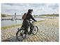 Fietser in regenjas en rugzak op e-bike aan het meer.