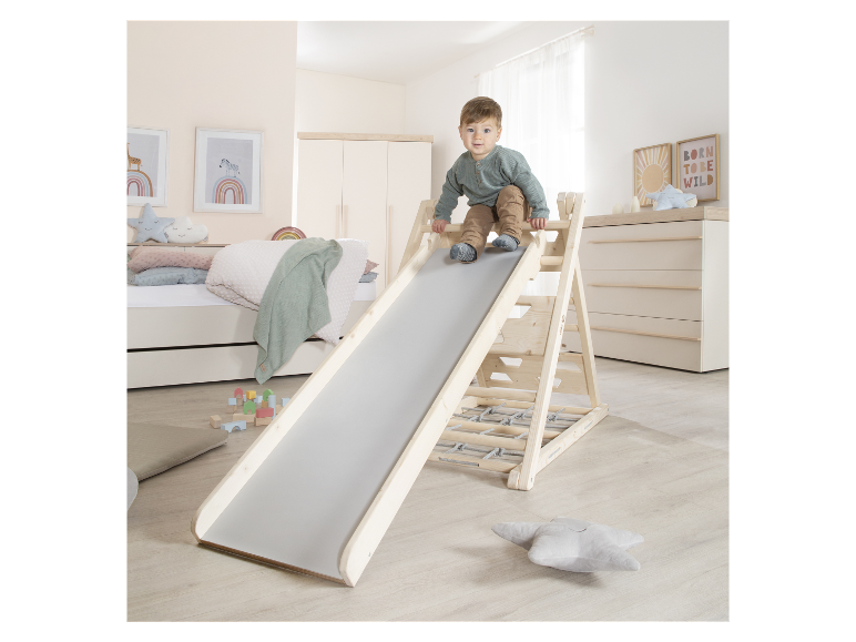 Een klein kind speelt op een houten glijbaan met klimwand.