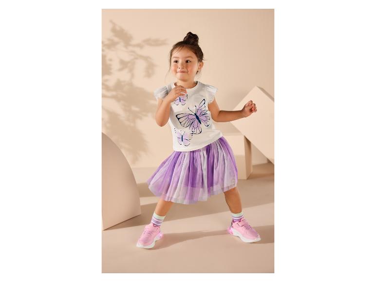 Meisje in wit T-shirt met vlinders en paarse tule rok, roze sneakers.