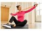 Vrouw in roze jack en zwarte legging traint met oranje weerstandsband.