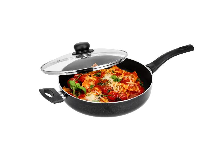 Zwarte pan met glazen deksel, gevuld met ravioli, cherrytomaten en basilicum