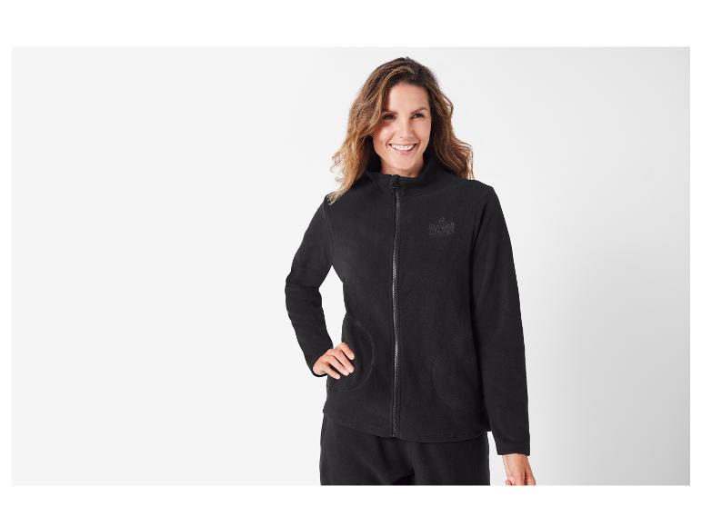 Een vrouw in een zwarte fleecejas met rits van het merk 'US Grand'.