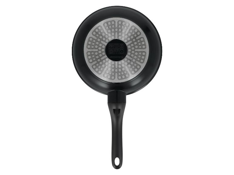 Onderkant van een zwarte koekenpan met een getextureerde zilveren basis en een zwart handvat.