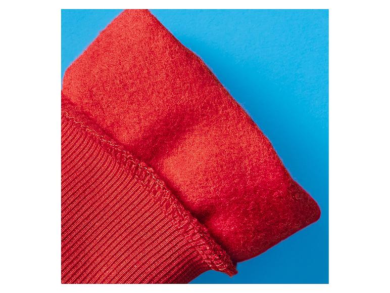 Rode stof, de ene geribbeld en de andere pluizig, op een blauwe achtergrond.