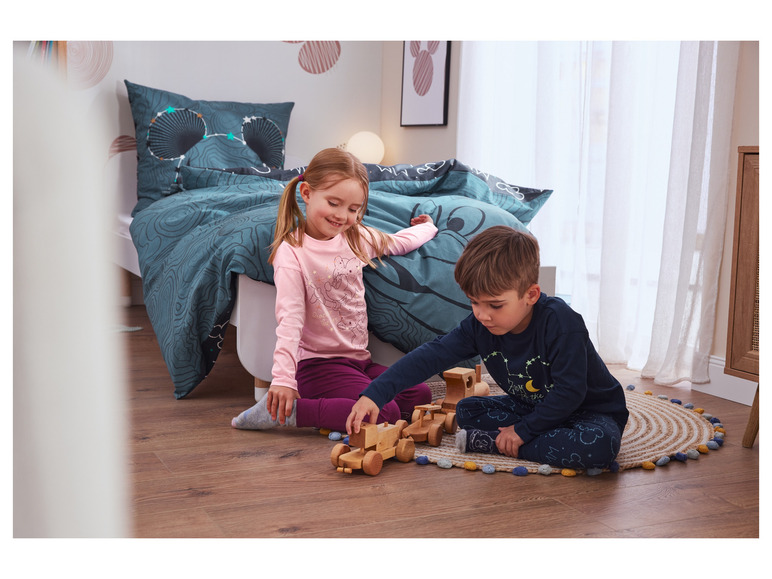 Twee kinderen spelen met houten speelgoed op een vloerkleed.