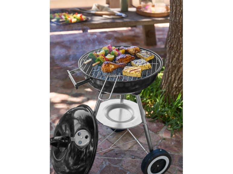 Houtskoolbarbecue met kip, halloumi en groentespiesjes buiten aan het koken.