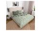 Slaapkamer met een bed met groen dekbedovertrek en kussens met bladpatroon, en een beige hoofdbord.