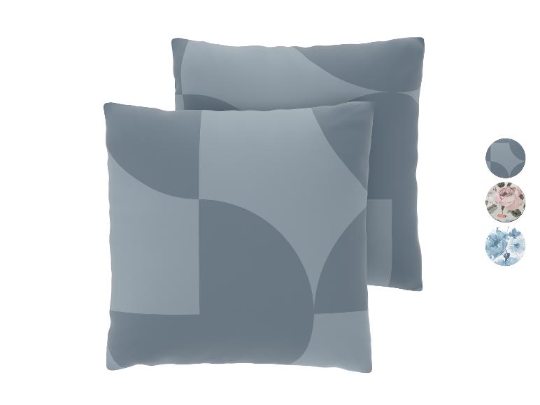 Twee decoratieve kussens met een grijs geometrisch patroon en stalen van bloemmotieven.