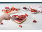 Hartvormige taart met fruit, gesneden, omringd door aardbeien, frambozen en kersen.