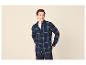 Man in een donkerblauw geruit overhemd over een wit T-shirt en donkere jeans.