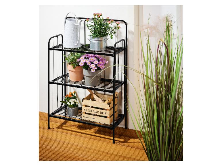 Zwart metalen rek met potplanten en een houten opbergdoos.