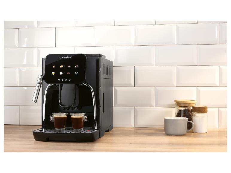 Zwart koffiezetapparaat met twee kopjes koffie, potten en een mok op een houten aanrecht.