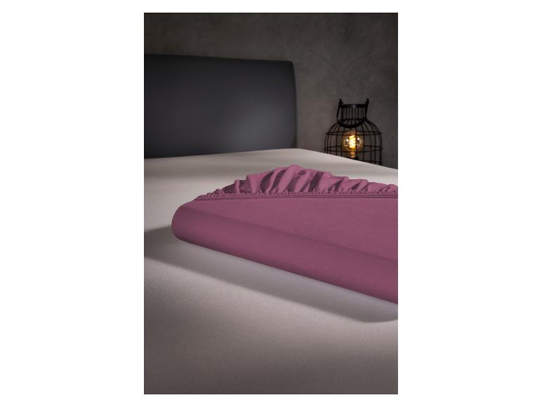 Paars hoeslaken op een bed, met een decoratieve lantaarn op de achtergrond.