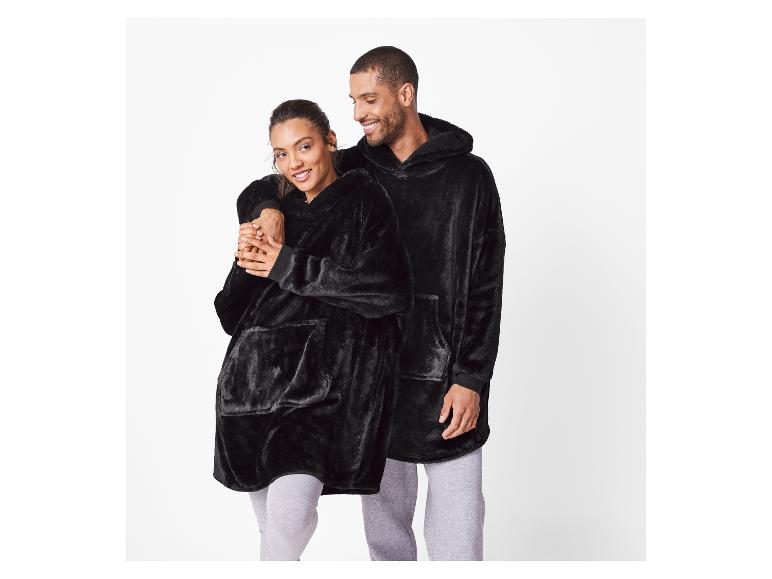 Paar in zwarte oversized hoodies en grijze joggingbroeken.