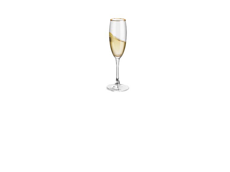 Een champagne glas met goudkleurige rand, gevuld met champagne.