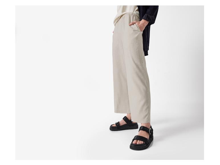 Beige wijde broek en zwarte sandalen: casual zomerlook.