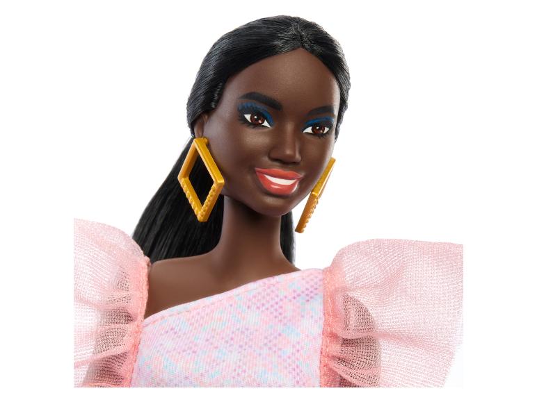 Barbiepop met een roze jurk met ruches en gouden oorbellen.