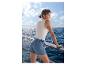 Vrouw in ESMARA® jeansshort op een boot met uitzicht op zee.