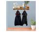 Houten kapstok met plank, lades en haken, met twee jassen, decoratie en planten.