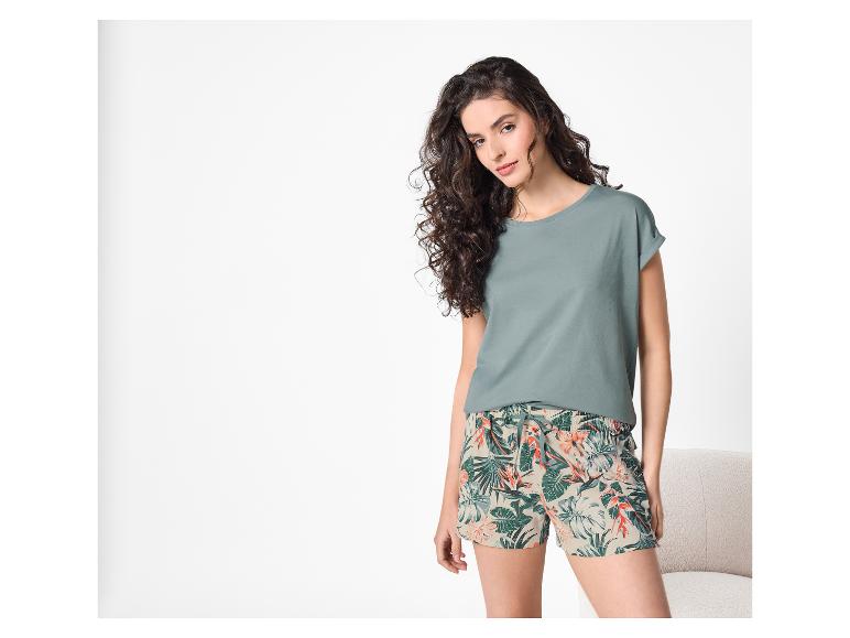Vrouw in een groen t-shirt en een korte broek met tropische print.
