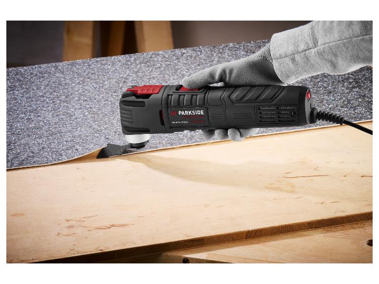 Multitool met mes snijdt vloerbedekking op een houten oppervlak.