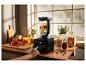Blender met fruit op aanrecht, met hand die startknop indrukt.