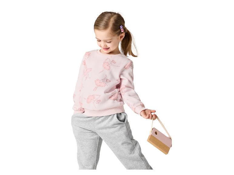 Meisje in roze sweatshirt met ballerina's en grijze joggingbroek, met houten tasje.