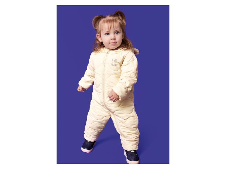 Peuter in een crèmekleurig sneeuwpak met een wasbeerontwerp.