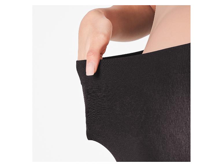 Een hand trekt aan de tailleband van een zwarte legging, wat de elasticiteit toont.