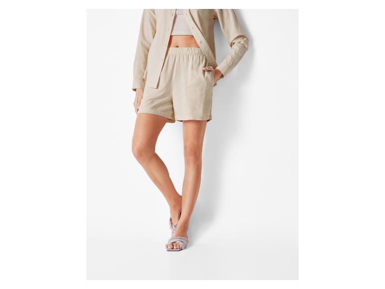 Beige linnen shorts en overhemd, platte sandalen.
