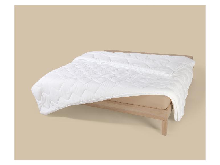 Wit gewatteerd dekbed op een bed met houten frame