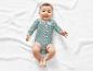 Een baby in een gestreept rompertje ligt op een witte deken.
