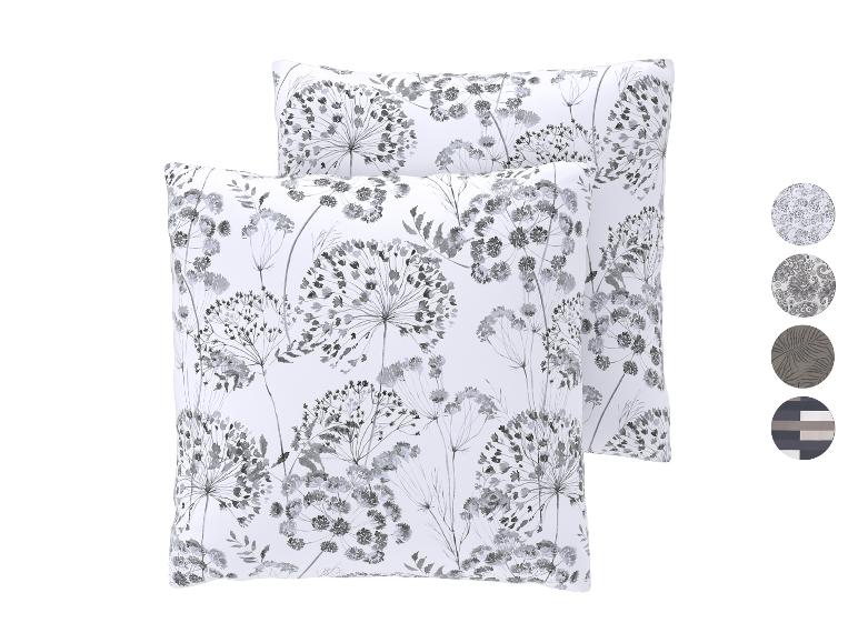 Twee witte kussens met een grijs bloemenpatroon en vier patroonstalen rechts