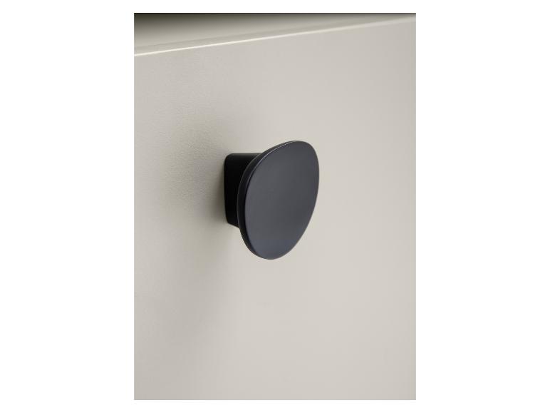 Close-up van een matzwarte, ronde handgreep op een lichtgrijze kastdeur.