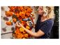 Vrouw gebruikt een STEINEL lijmpistool om oranje goudsbloemen aan een muur te bevestigen.