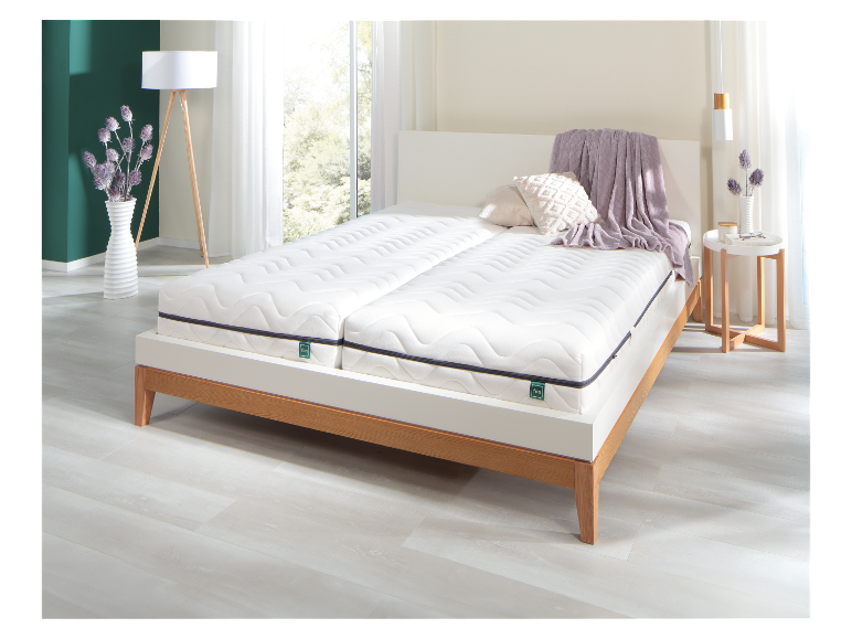 Dubbel Fan matras op een houten bed in een lichte, moderne slaapkamer.