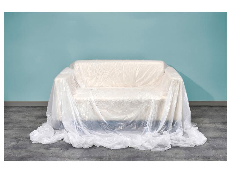 Bank bedekt met beschermend plastic voor een blauwe muur en betonnen vloer