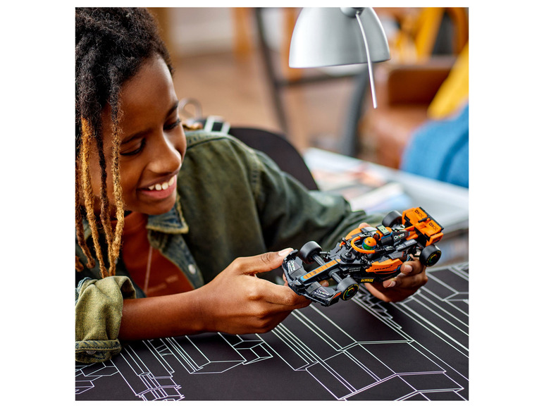 Een kind houdt een LEGO McLaren Formule 1 racewagen vast.