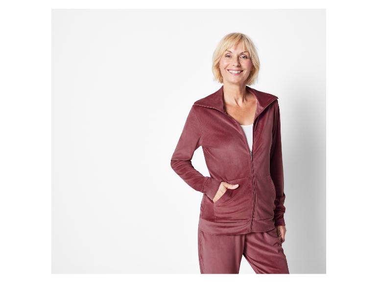 Een vrouw draagt een rode velours joggingbroek en -jas.