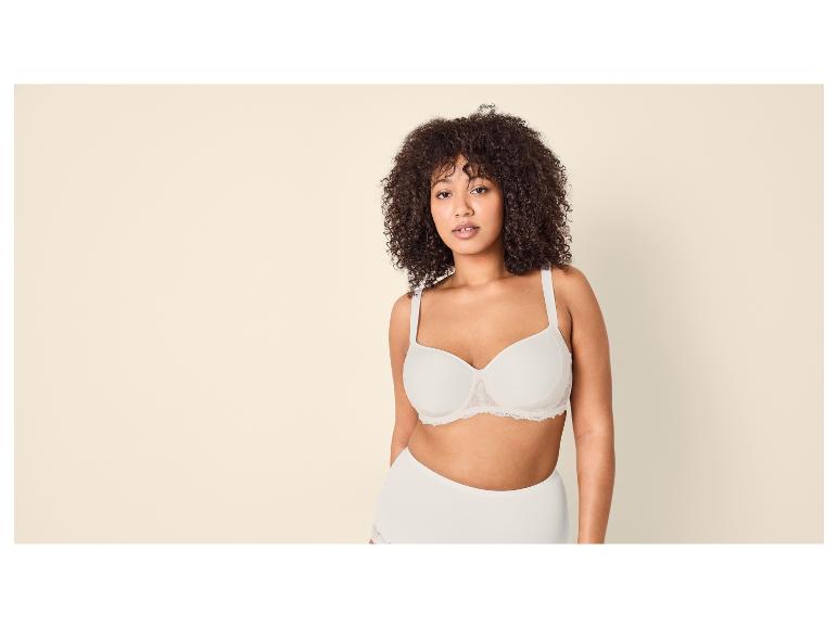 Vrouw met krullend haar in een witte beha en slip.